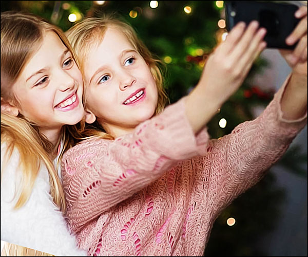 Deux enfants se prennent en photo avec leur téléphone à Noël