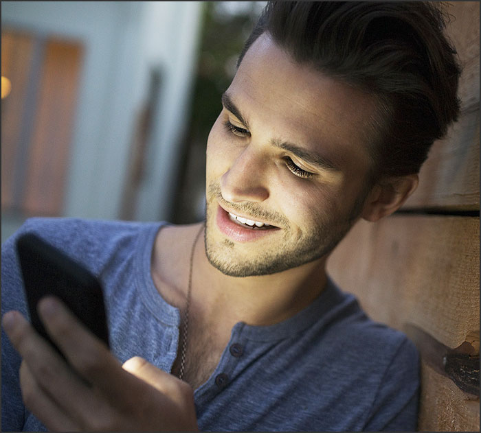 beau mec ebahi devant une discussion de drague sur son telephone