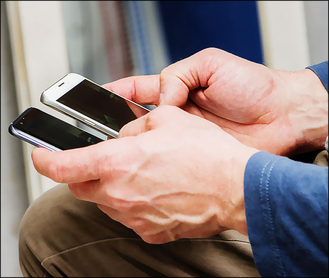 Un homme utilise deux téléphones