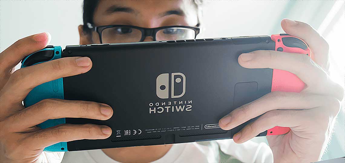 Personne tenant une console de jeu portable.