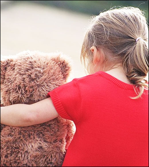 une petite fille de dos et son nounours