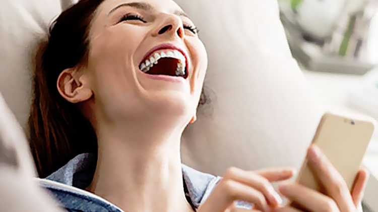 femme eclate de rire au telephone par sms