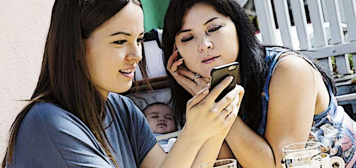 deux mamans regardent un telephone bebe qui dort