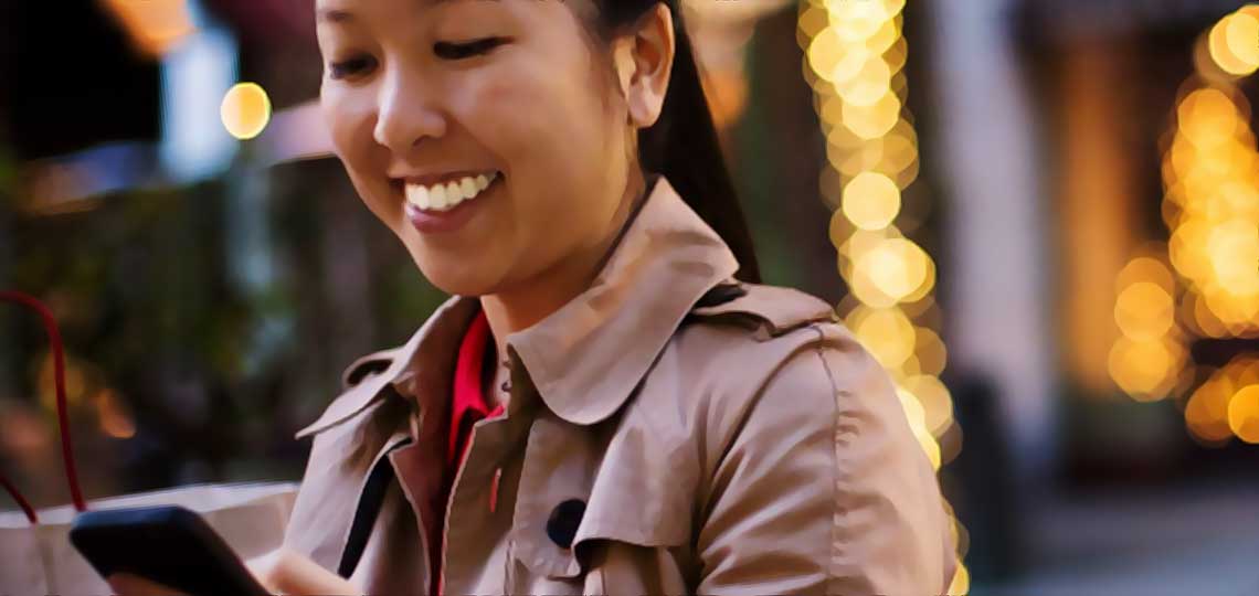 femme asiatique connectee avec son smartphone rayonne de joie