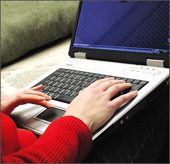 Utilisateur d'ordinateur portable en pull rouge.