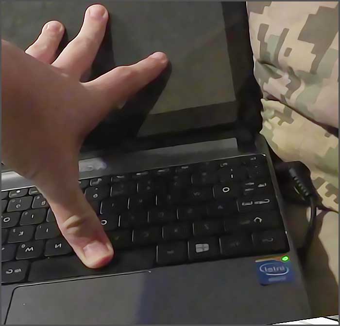 Main posée sur un clavier d'ordinateur portable.