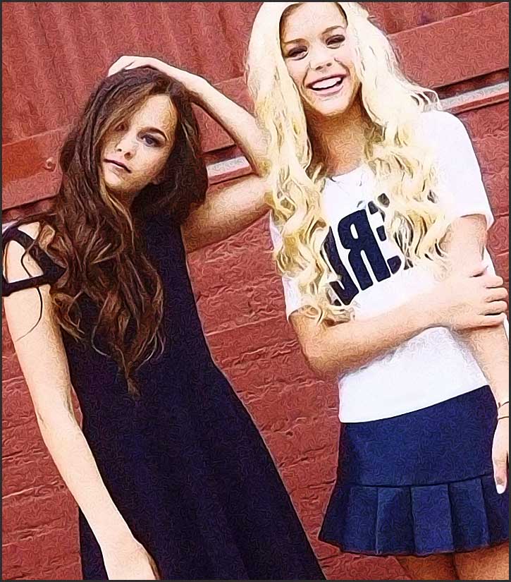 Deux amies souriantes devant un mur rouge, ressemblant à des adolescentes.