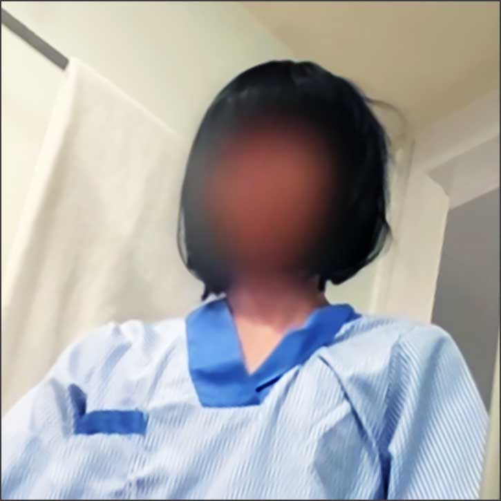 Personne avec blouse bleue, visage flouté.